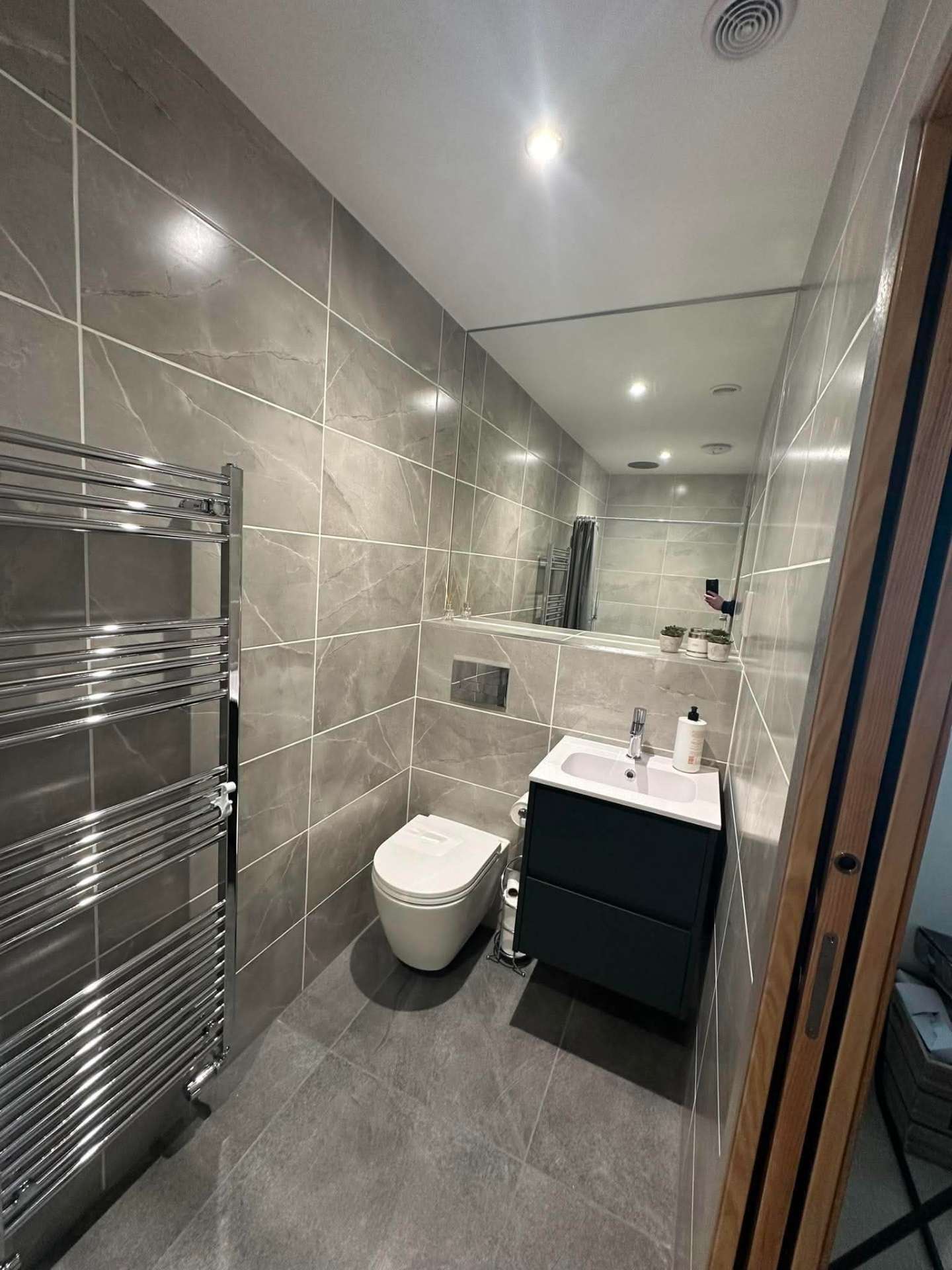 Grey tiled shower room with chrome towel radiator