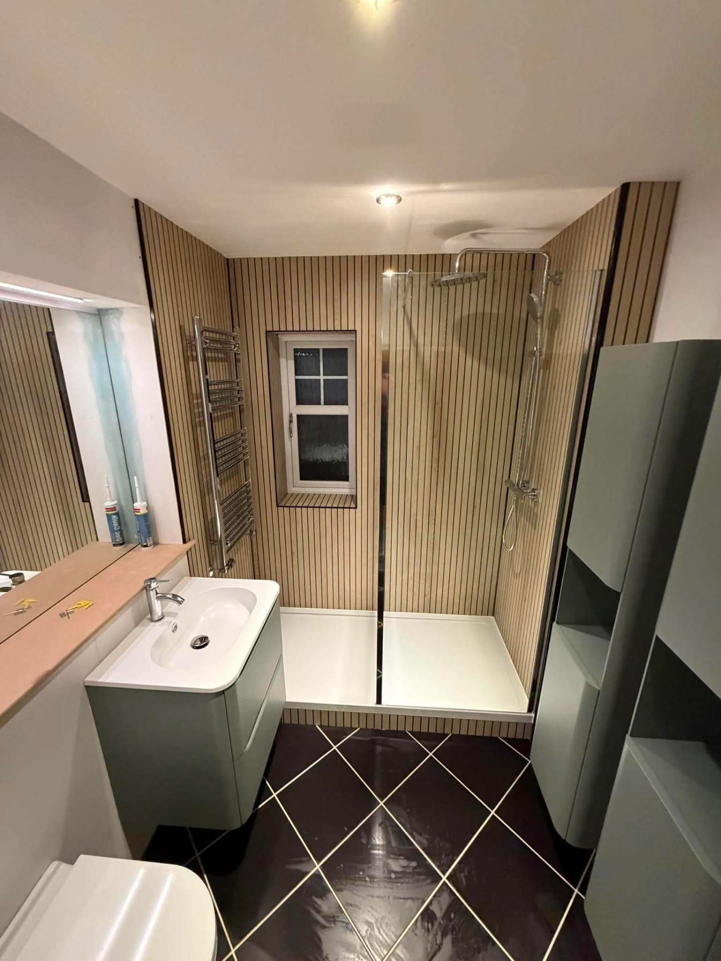 Shower room with slatted wood panelling, walk-in tray and chrome towel radiator