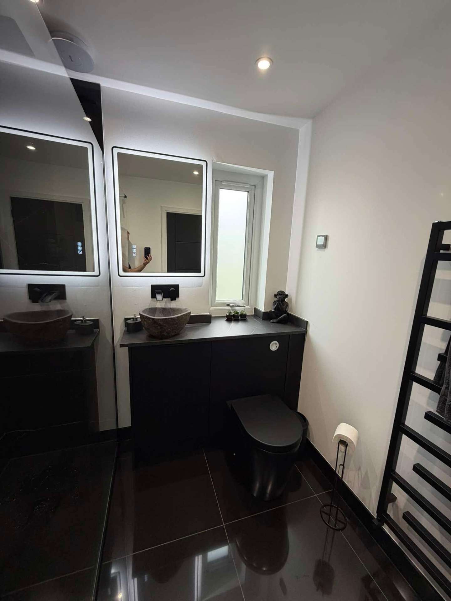 Modern bathroom with twin LED mirrors, stone vessel basins and black fittings